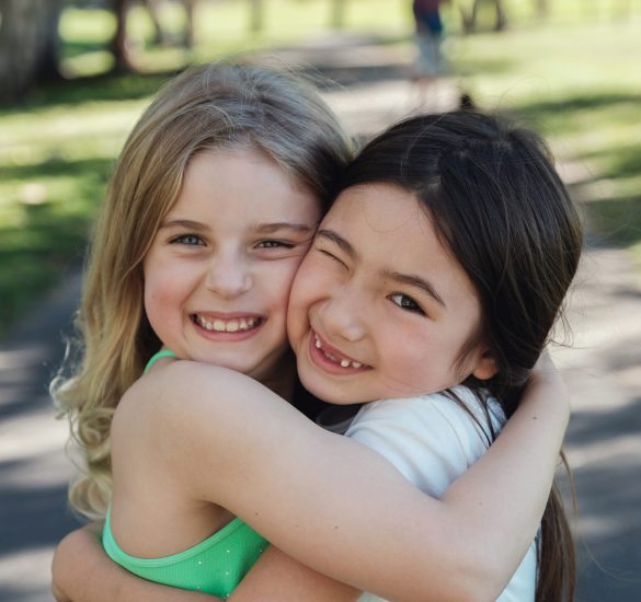 Happy and healthy mixed ethnic young little girls hugging and smiling in the park, best friends and friendship concept